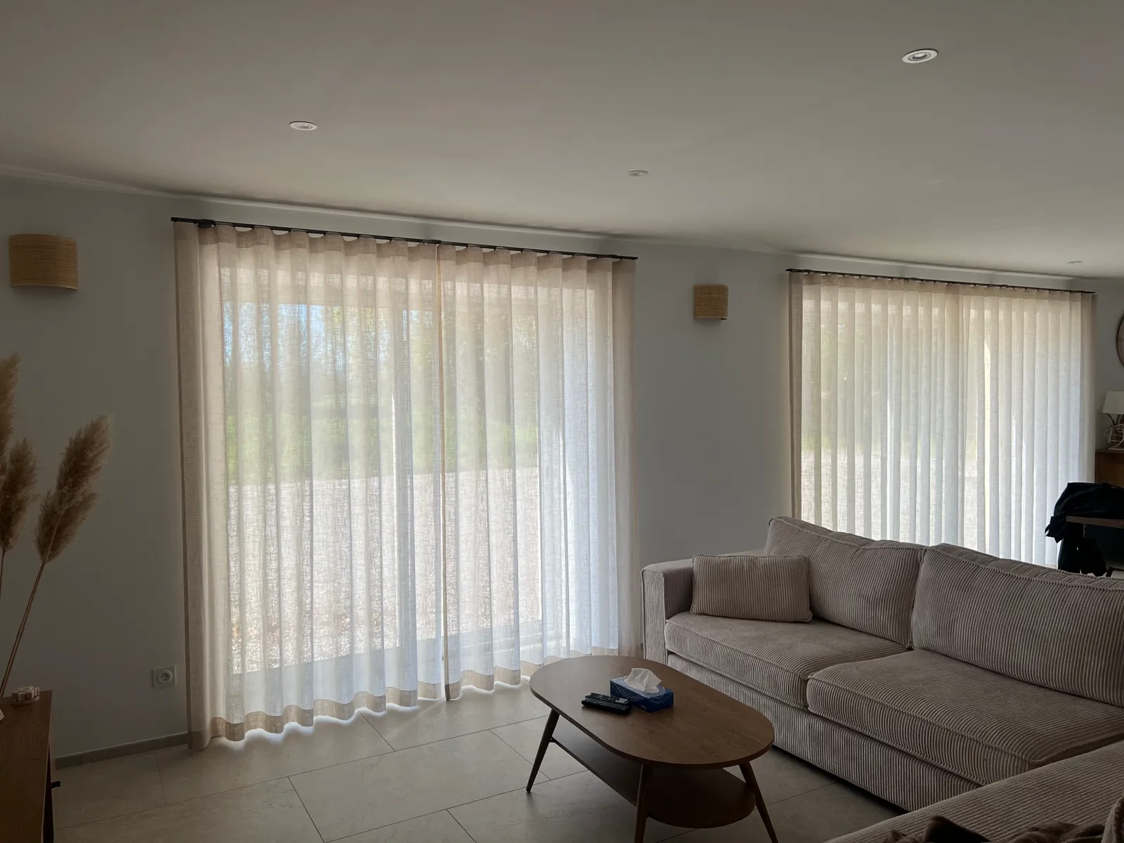 Voilages tamisants en lin sur double baie dans un séjour avec canapé velours côtelé