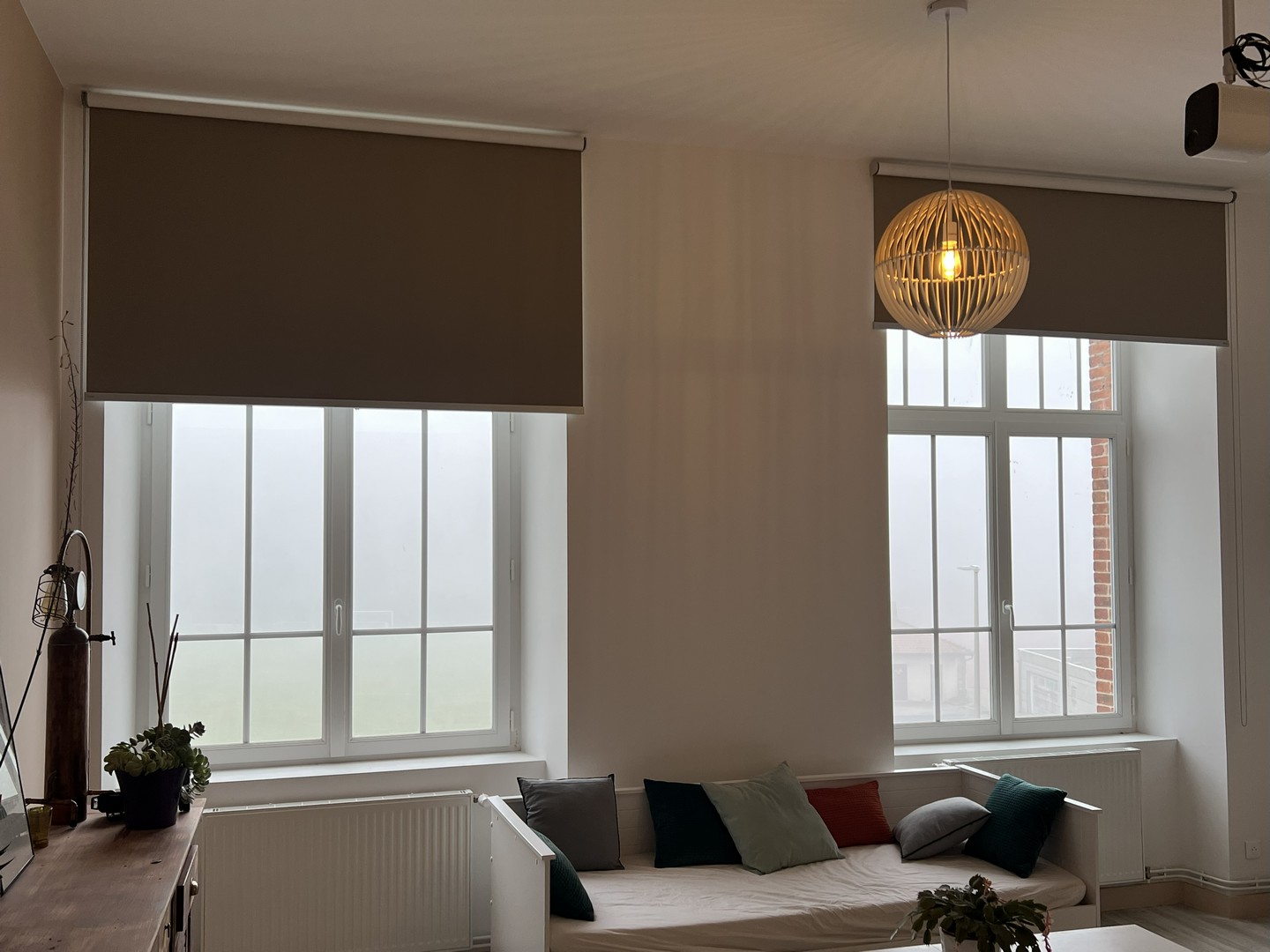 Stores enrouleurs occultants taupe dans un salon aux fenêtres cintrées