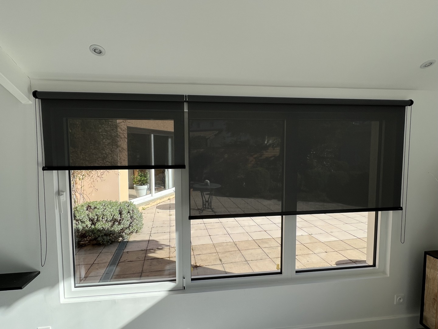 Stores enrouleurs screen sombres sur double fenêtre donnant sur terrasse