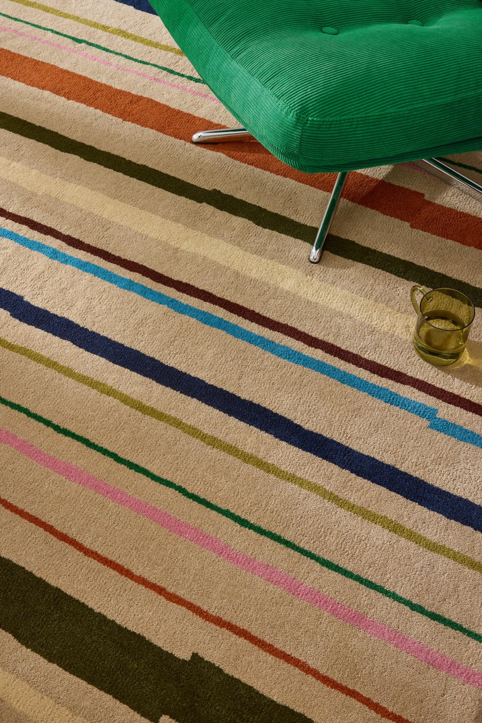 Tapis à rayures multicolores sous un fauteuil vert