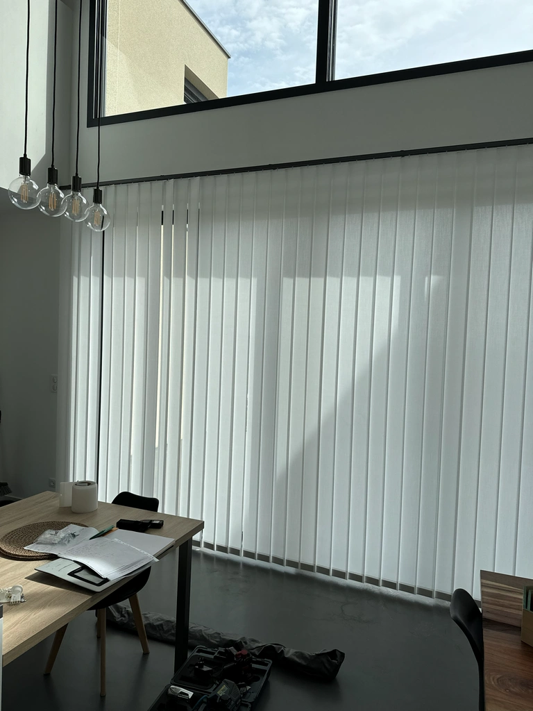 Stores à bandes verticales blancs dans un bureau lumineux